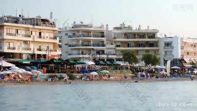 度假村在海边，许多人在海滩上和酒店在背景海在前景